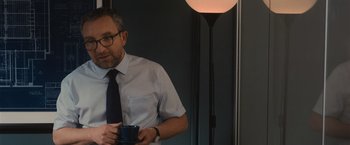 Movie still from “Wrath of Man” (2021), directed by Guy Ritchie – A man holding a coffee cup in his hand; Medium shot, Over the shoulder angle