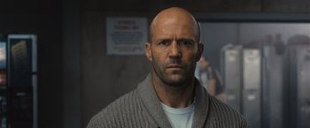 Movie still from “Wrath of Man” (2021), directed by Guy Ritchie – A man with a bald head wearing a sweater; Close Up shot, Low angle
