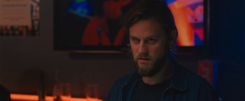 Movie still from “Wrath of Man” (2021), directed by Guy Ritchie – A man with long hair and a goatee stares at the camera; Close Up shot, Over the shoulder angle