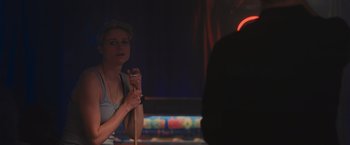 Movie still from “Wrath of Man” (2021), directed by Guy Ritchie – A woman is holding a stick in her hand; Close Up shot, Over the shoulder angle