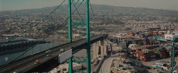 Movie still from “Wrath of Man” (2021), directed by Guy Ritchie – An aerial view of a bridge with a city in the background; Extreme Wide shot, High angle