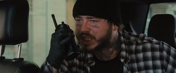 Movie still from “Wrath of Man” (2021), directed by Guy Ritchie – A man with tattoos on his face talking on a cell phone; Close Up shot, Low angle