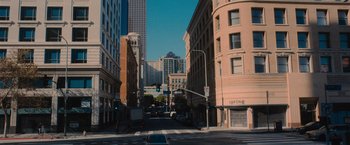 Movie still from “Wrath of Man” (2021), directed by Guy Ritchie – A city street lined with tall buildings near a traffic light; Extreme Wide shot, High angle