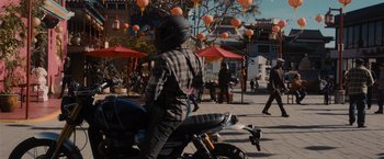 Movie still from “Wrath of Man” (2021), directed by Guy Ritchie – A person riding a motorcycle down a street; Wide shot, Over the shoulder angle