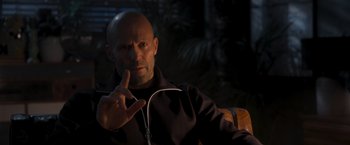 Movie still from “Wrath of Man” (2021), directed by Guy Ritchie – A bald man with a shaved head is listening to music; Close Up shot, Over the shoulder angle