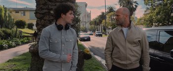 Movie still from “Wrath of Man” (2021), directed by Guy Ritchie – Two men standing next to each other on the side of the street; Medium shot, Over the shoulder angle