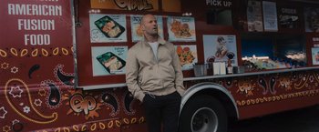Movie still from “Wrath of Man” (2021), directed by Guy Ritchie – A man standing in front of a food truck; Medium shot, Over the shoulder angle