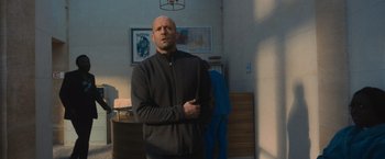 Movie still from “Wrath of Man” (2021), directed by Guy Ritchie – A man standing in a living room with his hands in his pockets; Medium shot, Low angle