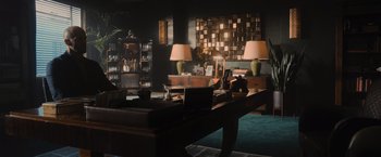 Movie still from “Wrath of Man” (2021), directed by Guy Ritchie – A living room with two lamps and a desk; Extreme Wide shot, High angle