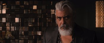 Movie still from “Wrath of Man” (2021), directed by Guy Ritchie – An older man with a beard and a jacket; Close Up shot, Low angle