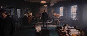 Movie still from “Wrath of Man” (2021), directed by Guy Ritchie – A man standing in front of a large painting in a room; Wide shot, Over the shoulder angle