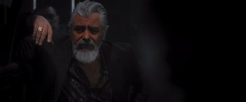 Movie still from “Wrath of Man” (2021), directed by Guy Ritchie – An old man with a gray beard and a black jacket; Close Up shot, Over the shoulder angle