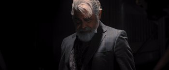 Movie still from “Wrath of Man” (2021), directed by Guy Ritchie – An older man with a beard and a suit; Medium shot, Low angle