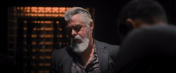 Movie still from “Wrath of Man” (2021), directed by Guy Ritchie – A man with a gray beard is looking at the camera; Close Up shot, Over the shoulder angle