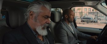 Movie still from “Wrath of Man” (2021), directed by Guy Ritchie – Two men sitting in the back seat of a car; Close Up shot, Over the shoulder angle