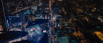 Movie still from “Wrath of Man” (2021), directed by Guy Ritchie – An aerial view of a city at night with lights; Extreme Wide shot, High angle