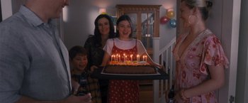 Movie still from “Wrath of Man” (2021), directed by Guy Ritchie – A group of people standing around a birthday cake; Medium shot, High angle