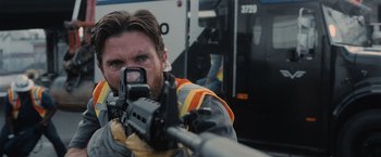 Movie still from “Wrath of Man” (2021), directed by Guy Ritchie – A person holding a rifle; Close Up shot, Low angle