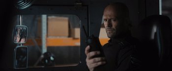 Movie still from “Wrath of Man” (2021), directed by Guy Ritchie – A man holding a cell phone in his hand; Close Up shot, Low angle