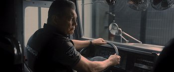 Movie still from “Wrath of Man” (2021), directed by Guy Ritchie – A man in a police uniform sitting in a car; Close Up shot, Over the shoulder angle