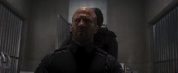 Movie still from “Wrath of Man” (2021), directed by Guy Ritchie – A man in a black shirt is looking at the camera; Close Up shot, Low angle