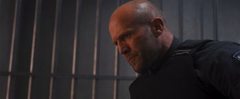 Movie still from “Wrath of Man” (2021), directed by Guy Ritchie – A man with a bald head in front of a jail cell; Close Up shot, Low angle