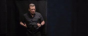 Movie still from “Wrath of Man” (2021), directed by Guy Ritchie – A man in a black shirt is holding a knife; Medium shot, Low angle