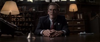 Movie still from “X-Men: First Class” (2011), directed by Matthew Vaughn – A man sitting at a table in a room; Close Up shot, Low angle