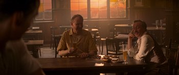 Movie still from “X-Men: First Class” (2011), directed by Matthew Vaughn – A man sitting at a table with a glass of beer in front of him; Medium shot, Over the shoulder angle
