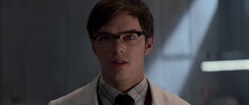 Movie still from “X-Men: First Class” (2011), directed by Matthew Vaughn – A young man wearing glasses and a lab coat; Close Up shot, Over the shoulder angle