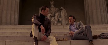 Movie still from “X-Men: First Class” (2011), directed by Matthew Vaughn – Two men are sitting on the steps of a building and one is playing chess; Medium shot, Low angle