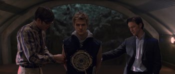 Movie still from “X-Men: First Class” (2011), directed by Matthew Vaughn – A young man is being fitted for a costume by two men; Medium shot, Over the shoulder angle