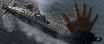 Movie still from “X-Men: First Class” (2011), directed by Matthew Vaughn – A man is standing in front of a boat in the water; Extreme Wide shot, Overhead angle