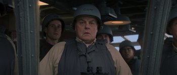 Movie still from “X-Men: First Class” (2011), directed by Matthew Vaughn – An older man wearing a helmet while standing in front of other men; Close Up shot, Low angle