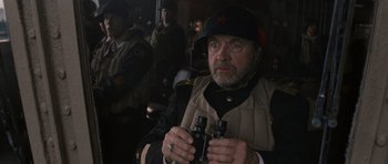 Movie still from “X-Men: First Class” (2011), directed by Matthew Vaughn – An older man holding two binoculars while standing in front of other men; Close Up shot, Over the shoulder angle