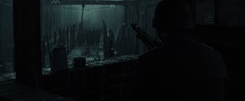 Movie still from “X-Men” (2000), directed by Bryan Singer – A man standing next to a brick wall in the rain; Wide shot, Over the shoulder angle