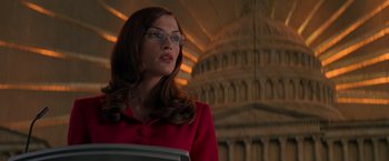 Movie still from “X-Men” (2000), directed by Bryan Singer – A woman in a red coat and glasses is standing in front of the capitol building; Medium shot, Low angle