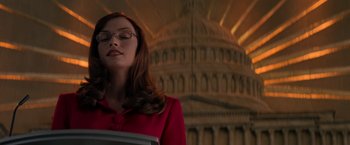 Movie still from “X-Men” (2000), directed by Bryan Singer – A woman in a red dress is standing in front of a building; Medium shot, Low angle