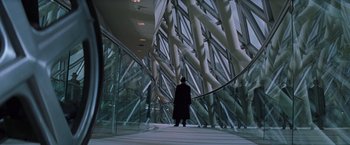 Movie still from “X-Men” (2000), directed by Bryan Singer – A man in a top hat stands in front of an escalator; Wide shot, Low angle