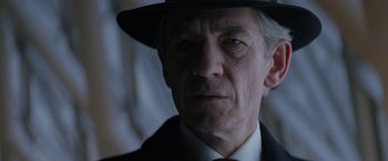 Movie still from “X-Men” (2000), directed by Bryan Singer – An older man wearing a black hat and a suit; Close Up shot, Low angle