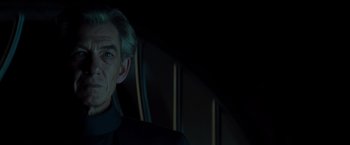 Movie still from “X-Men” (2000), directed by Bryan Singer – An older man in a black suit is looking at the camera; Close Up shot, Over the shoulder angle