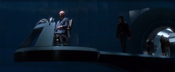Movie still from “X-Men” (2000), directed by Bryan Singer – A man sitting in a chair next to a woman; Wide shot, High angle