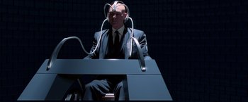 Movie still from “X-Men” (2000), directed by Bryan Singer – A man sitting at a desk with wires attached to his head; Medium shot, High angle