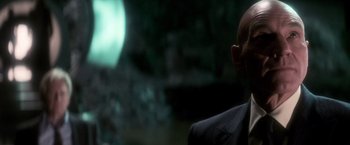 Movie still from “X-Men” (2000), directed by Bryan Singer – A man in a suit and tie looking at the camera; Close Up shot, Over the shoulder angle