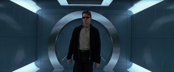 Movie still from “X-Men” (2000), directed by Bryan Singer – A man wearing sunglasses standing in front of a wall; Medium shot, Low angle