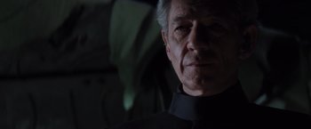 Movie still from “X-Men” (2000), directed by Bryan Singer – An older man wearing a black shirt and a black tie; Close Up shot, Low angle