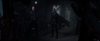 Movie still from “X-Men” (2000), directed by Bryan Singer – Two women dressed in black are standing next to each other in a dark room; Wide shot, Low angle