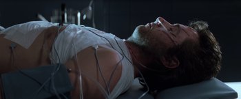 Movie still from “X-Men” (2000), directed by Bryan Singer – A man laying on a bed with wires attached to his chest; Close Up shot, High angle