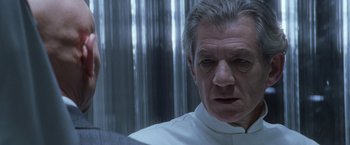 Movie still from “X-Men” (2000), directed by Bryan Singer – An older man in a white shirt looking at the camera; Close Up shot, Over the shoulder angle
