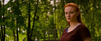 Movie still from “X-Men: Apocalypse” (2016), directed by Bryan Singer – A beautiful young woman with red hair standing next to a fence; Close Up shot, Over the shoulder angle
